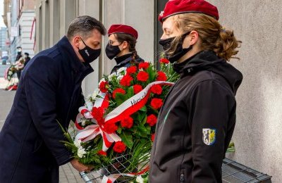 Kwiaty pod tablicą upamiętniającą siedzibę Po